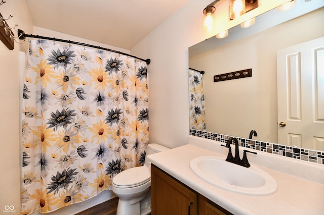 bathroom featuring vanity, decorative backsplash, toilet, and walk in shower