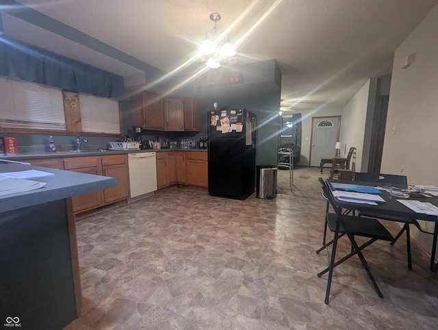 kitchen featuring black fridge, sink, an inviting chandelier, and white dishwasher