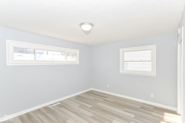 empty room with light hardwood / wood-style floors and a textured ceiling