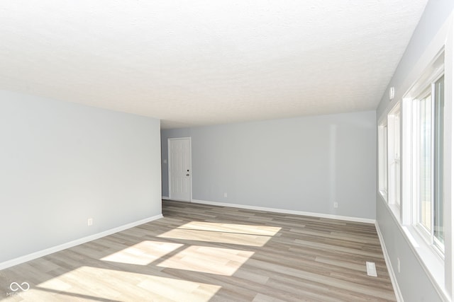 unfurnished room with hardwood / wood-style flooring and a textured ceiling