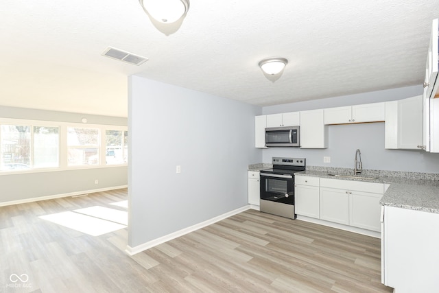 kitchen featuring sink, stainless steel appliances, light hardwood / wood-style floors, and white cabinets