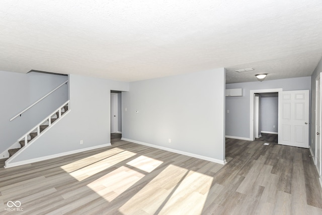 unfurnished living room featuring hardwood / wood-style flooring and a textured ceiling