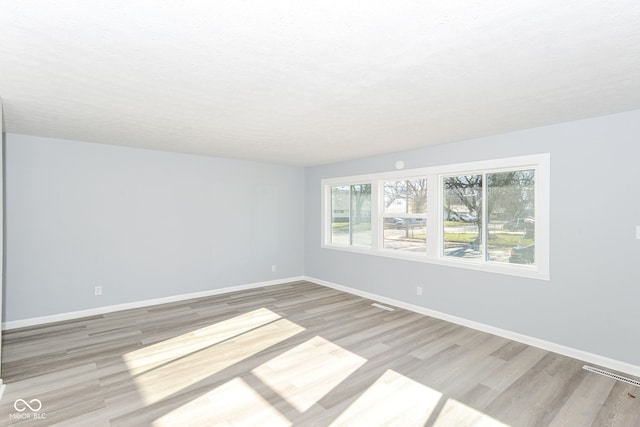 unfurnished room with a textured ceiling and light wood-type flooring