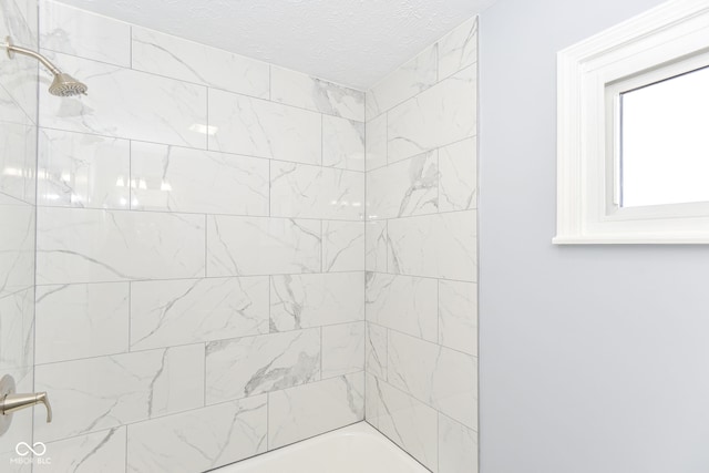 bathroom with tiled shower / bath and a textured ceiling