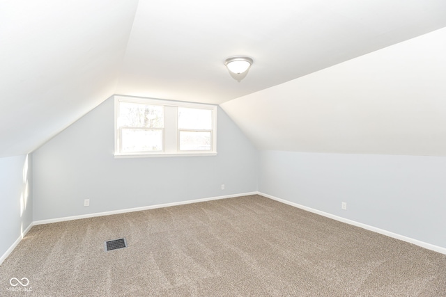 additional living space featuring lofted ceiling and carpet flooring