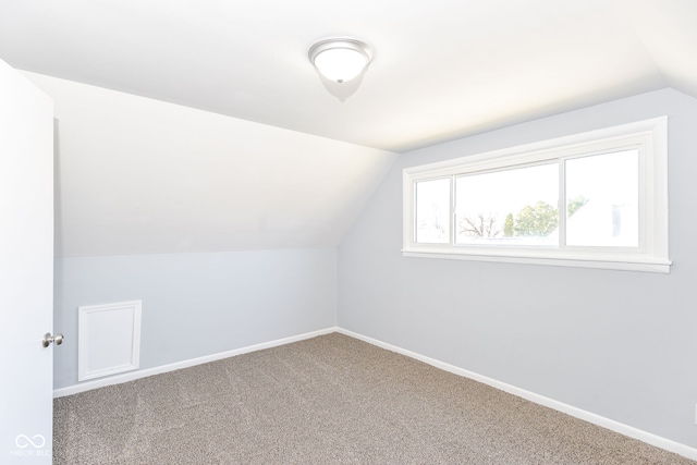 bonus room with vaulted ceiling and carpet flooring