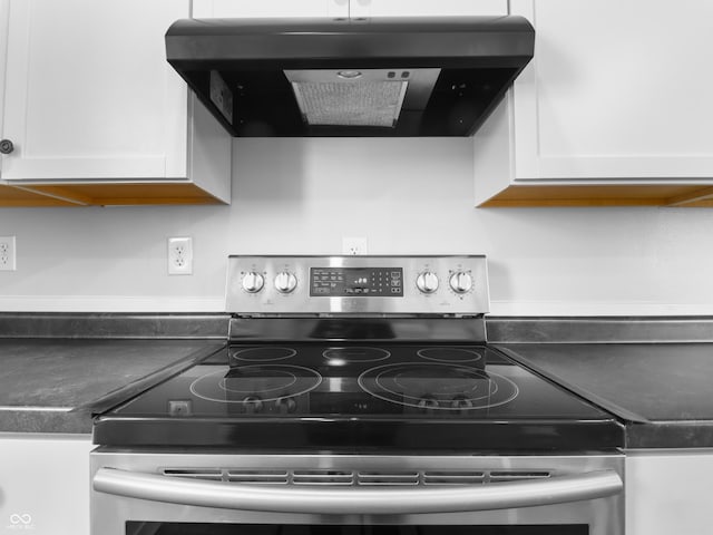 kitchen with ventilation hood, stainless steel range with electric cooktop, and white cabinets