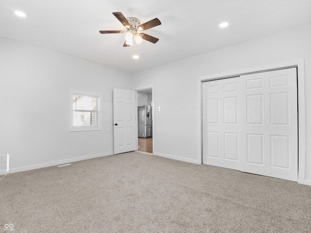 unfurnished bedroom with a closet, carpet floors, ceiling fan, and stainless steel fridge with ice dispenser