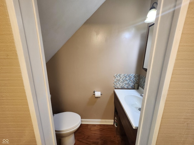 bathroom featuring hardwood / wood-style flooring, vanity, vaulted ceiling, and toilet