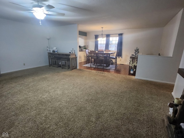 interior space with dark carpet and ceiling fan with notable chandelier