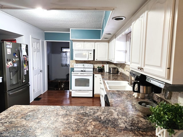 kitchen with sink, backsplash, white cabinets, and white appliances