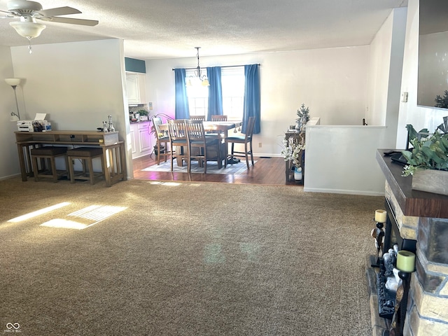 dining area with dark carpet, ceiling fan with notable chandelier, and a textured ceiling