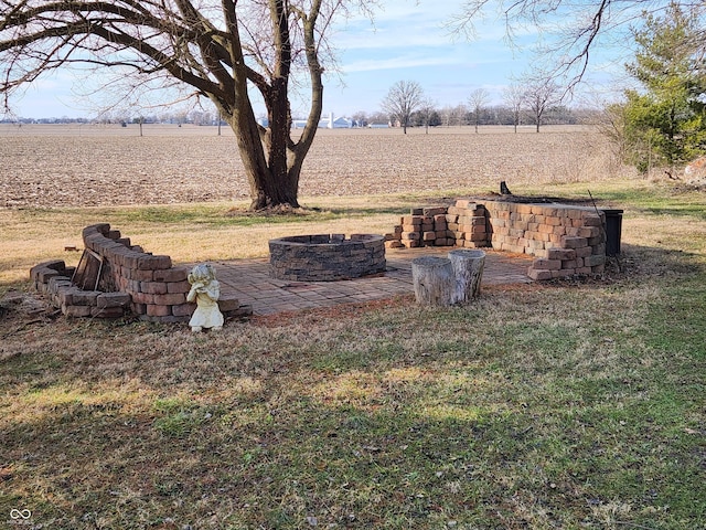 view of yard with an outdoor fire pit and a rural view