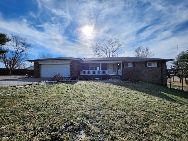 ranch-style home featuring a garage, covered porch, and a front lawn