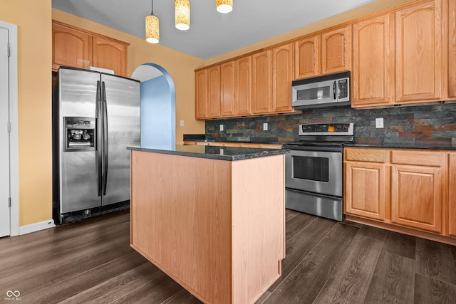 kitchen with appliances with stainless steel finishes, dark hardwood / wood-style flooring, a kitchen island, pendant lighting, and backsplash