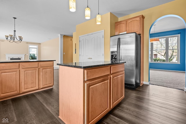 kitchen featuring stainless steel fridge with ice dispenser, decorative light fixtures, a healthy amount of sunlight, and a kitchen island