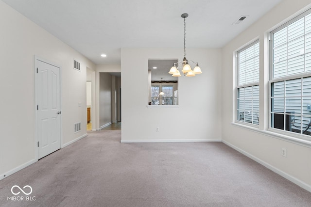 carpeted empty room featuring a wealth of natural light and a notable chandelier