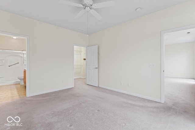 unfurnished bedroom featuring a walk in closet, connected bathroom, and light carpet