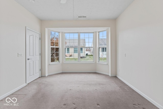 carpeted empty room with ceiling fan and a textured ceiling