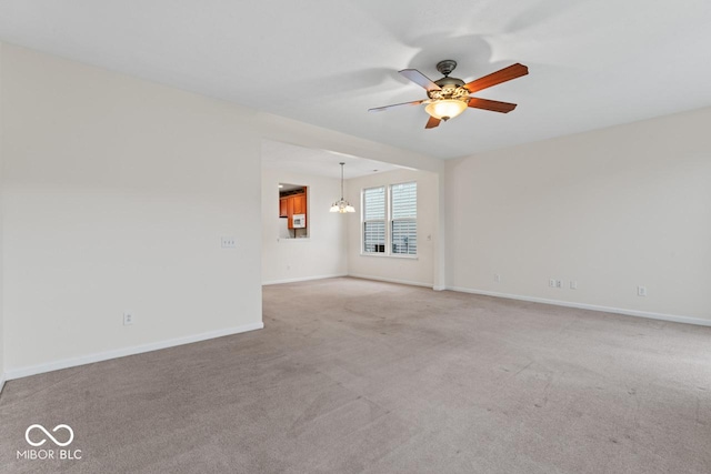 carpeted spare room featuring ceiling fan with notable chandelier