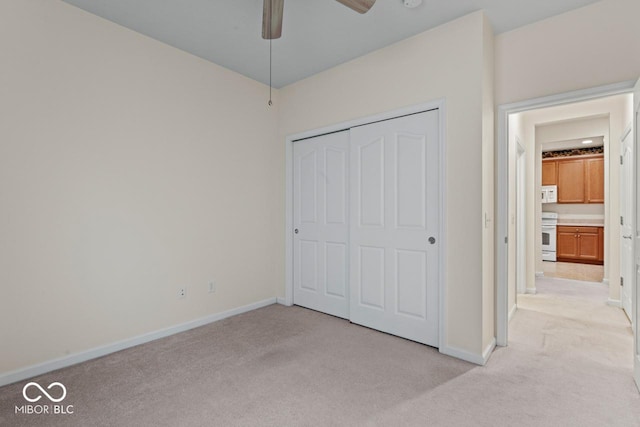 unfurnished bedroom with light carpet, a closet, and ceiling fan