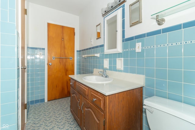 bathroom featuring vanity, toilet, and tile walls