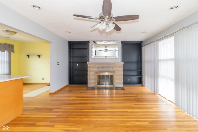 unfurnished living room with ceiling fan, wood-type flooring, and a fireplace