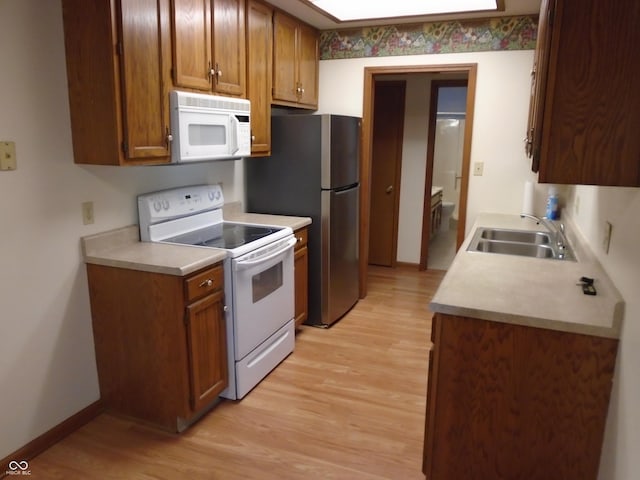 kitchen with white appliances, light hardwood / wood-style floors, and sink