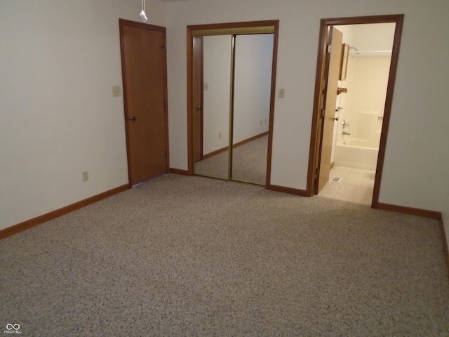 unfurnished bedroom featuring light colored carpet, a closet, and ensuite bathroom