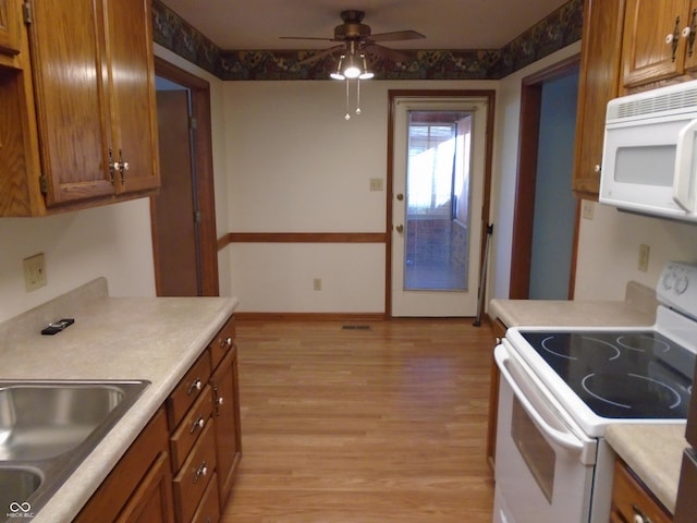 kitchen with sink, white appliances, light hardwood / wood-style flooring, and ceiling fan