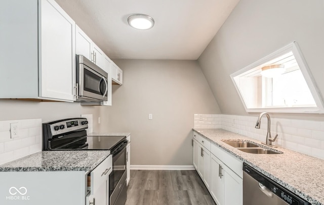 kitchen with sink, light stone counters, stainless steel appliances, decorative backsplash, and white cabinets