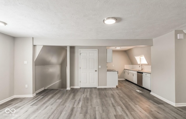 basement with sink, a textured ceiling, and light wood-type flooring