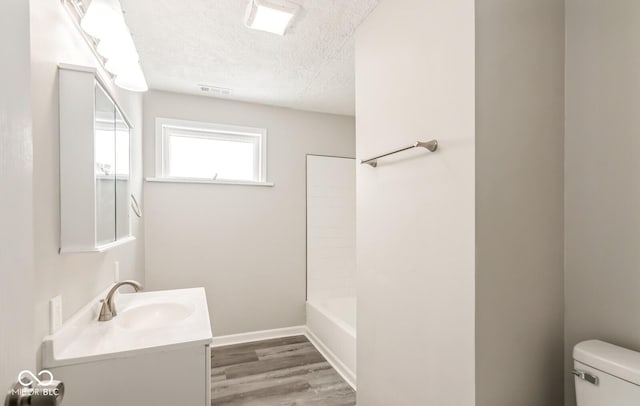 full bathroom with shower / tub combination, vanity, wood-type flooring, a textured ceiling, and toilet