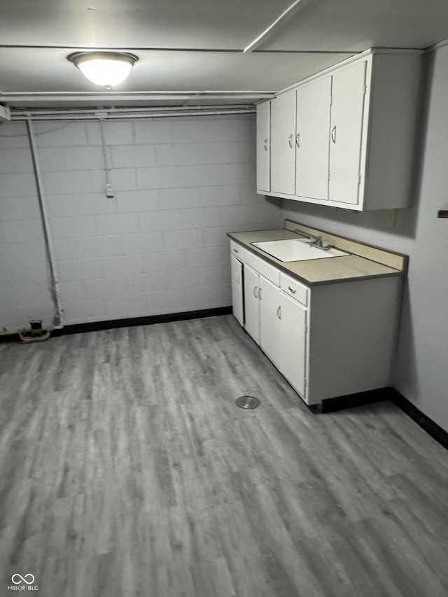 clothes washing area with sink and light hardwood / wood-style floors