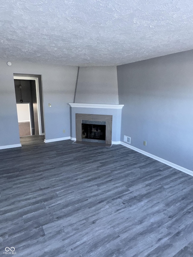 unfurnished living room with a premium fireplace, dark hardwood / wood-style floors, and a textured ceiling