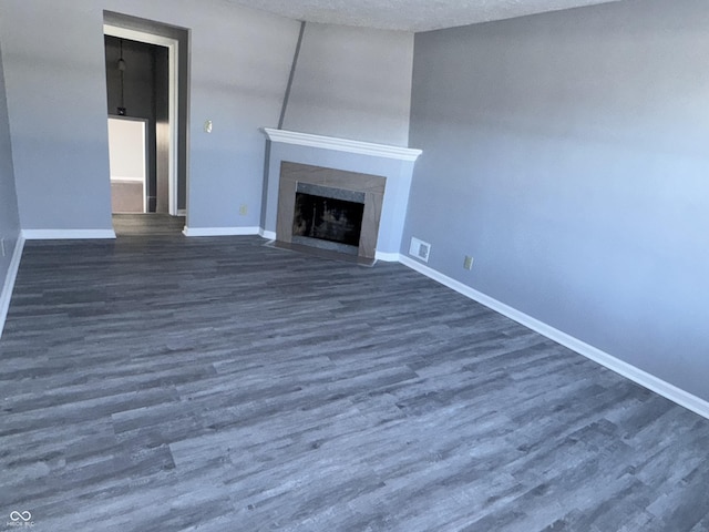 unfurnished living room featuring dark wood-type flooring and a textured ceiling