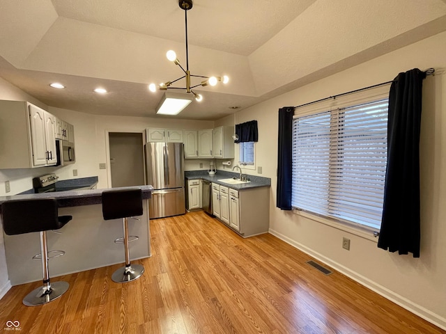 kitchen featuring a breakfast bar, sink, kitchen peninsula, stainless steel appliances, and light hardwood / wood-style floors