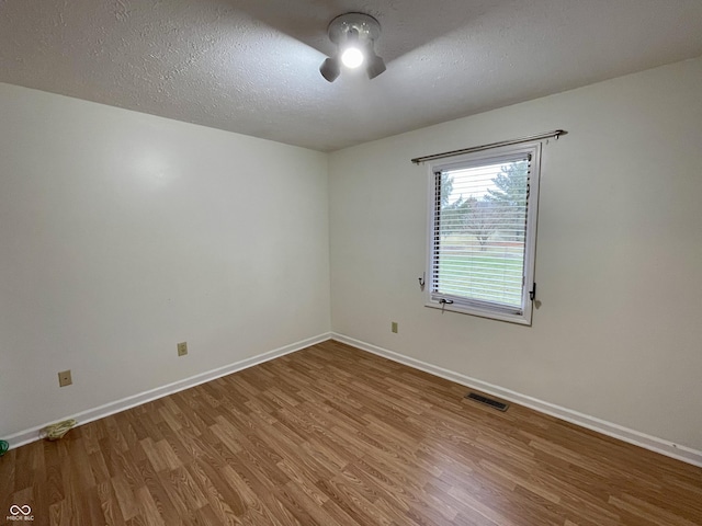 empty room with ceiling fan, wood-type flooring, and a textured ceiling