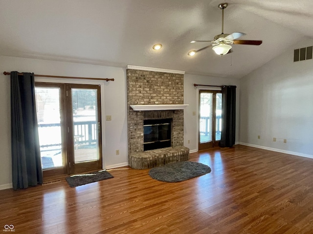 unfurnished living room with lofted ceiling, dark wood-style flooring, a fireplace, visible vents, and a ceiling fan