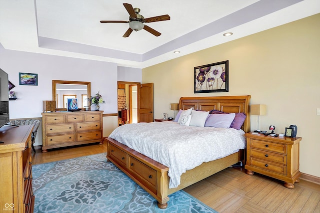 bedroom with ceiling fan and a tray ceiling