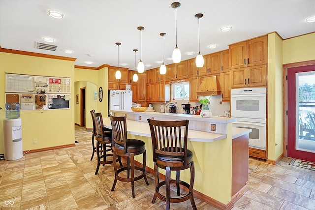 kitchen with premium range hood, a breakfast bar, a kitchen island, pendant lighting, and white appliances