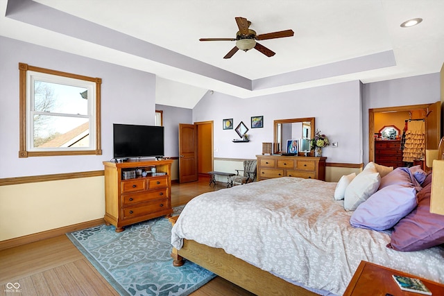 bedroom featuring ceiling fan, a tray ceiling, and light hardwood / wood-style floors