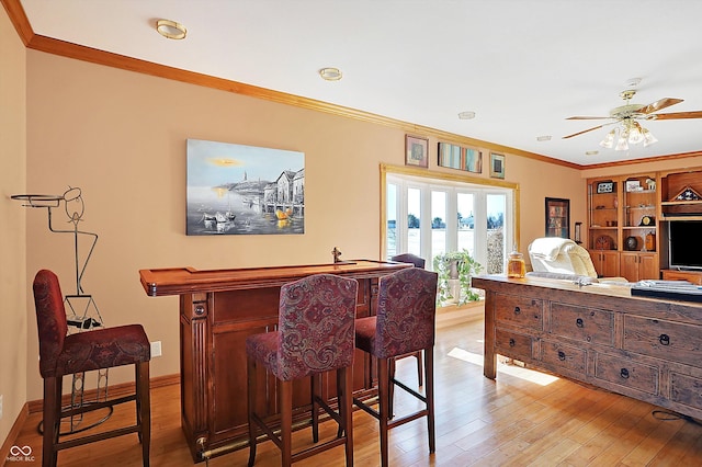 interior space featuring ornamental molding, indoor bar, ceiling fan, and light wood-type flooring