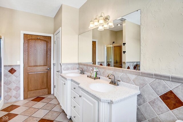 bathroom featuring tile patterned flooring, vanity, tile walls, and a shower with shower door