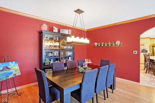 dining area with crown molding, wood-type flooring, and an inviting chandelier