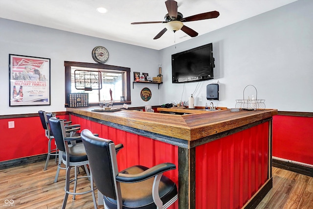 bar featuring hardwood / wood-style flooring, wood counters, and ceiling fan