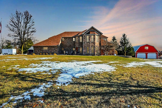 view of front facade with a garage, an outdoor structure, and a lawn