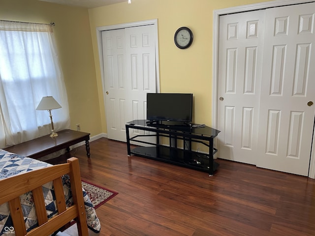 bedroom with multiple closets and dark hardwood / wood-style flooring