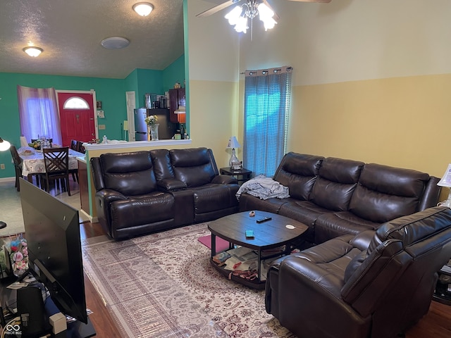 living room featuring hardwood / wood-style flooring, ceiling fan, vaulted ceiling, and a textured ceiling