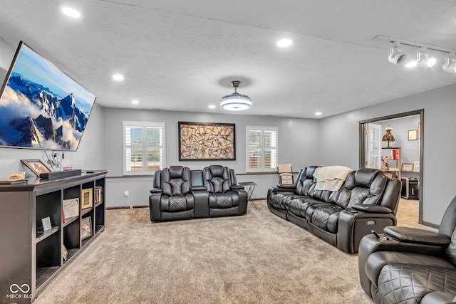 carpeted home theater room featuring rail lighting and a textured ceiling